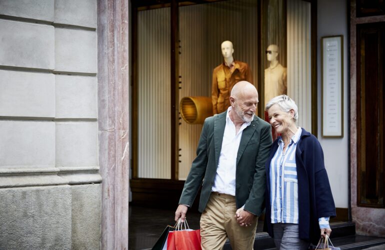 Happy senior couple with shopping bags walking by store