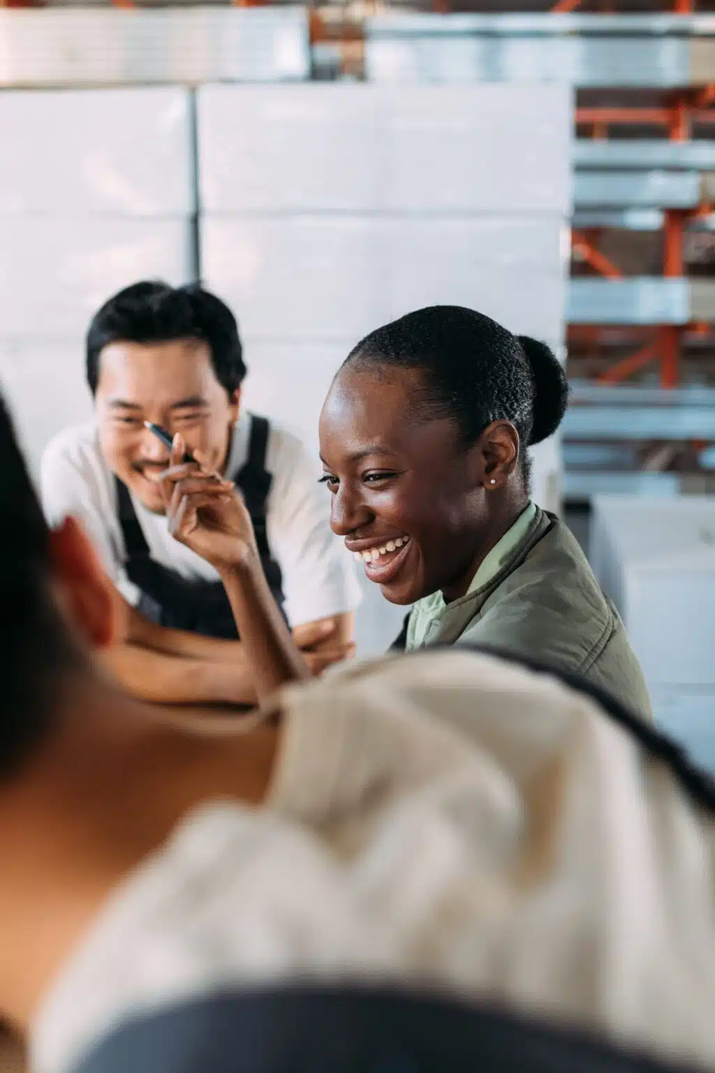 Portrait of three people working in factory, talking and laughing